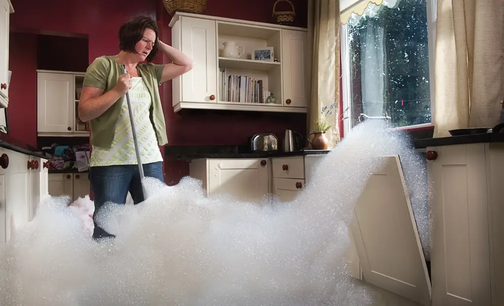 woman looks in despair as the kitchen gets flooded